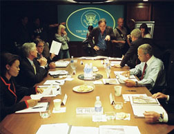 Director Oliver Stone (standing, center) on the set of his film W., with (left to right, seated) Condoleezza Rice (Thandie Newton), Donald Rumsfeld (Scott Glenn), George Tenet (Bruce McGill), George W. Bush (Josh Brolin, seated on table), Colin Powell (Jeffrey Wright) and Dick Cheney (Richard Dreyfuss). Photo credit: Sidney Ray Baldwin. Click image to expand.
