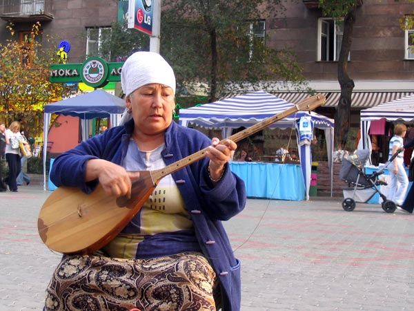 A Kazakh woman plays the dombra, a traditional instrument.