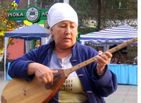 A Kazakh woman plays the dombra, a traditional instrument. Click image to expand.