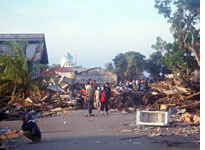 Villagers wearing surgical masks rummage through debris