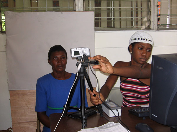 A registration worker prepares a digital photo of a Haitian woman for her identification card.