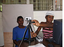 A registration worker prepares a digital photo of a Haitian woman for her identification card. Click image to expand.