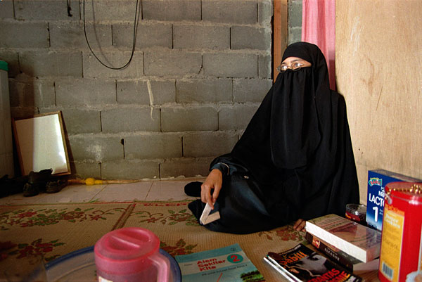 Paridah seated on the floor in her two-room shack in Tenggulun.