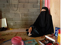 Paridah seated on the floor in her two-room shack in Tenggulun. Click image to expand.