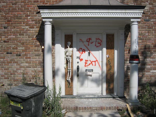 Early Halloween decoration on a boarded-up door frame.