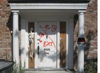 Early Halloween decoration on a boarded-up door frame. Click image to expand.