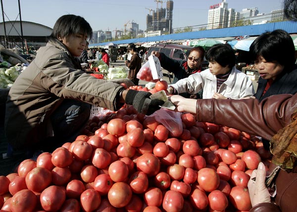 A Chinese vendor sells tomatoes to customers.