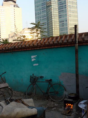 Scrap-burning stove against alley wall.