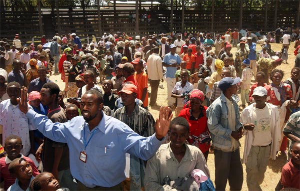 A local official tries to calm a group of Kikuyu refugees during a distribution of clothing.