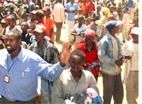 A local official tries to calm a group of Kikuyu refugees during a distribution of clothing
Click image to expand.