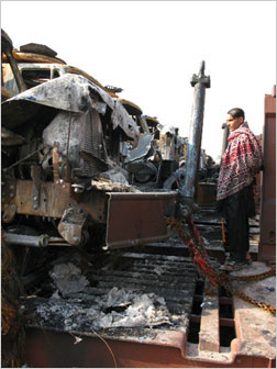 Mohammad Rehan, a watchman at a transport lot attacked by the Taliban, surveys ruined
vehicles.