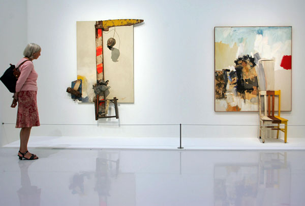 A woman views artwork by Robert Rauschenberg.