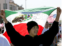 A demonstrator carries a Mexican flag. Click image to expand.