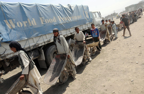 Afghan men wait in line to recieve staple goods during the distribution of food from the World Food Program.