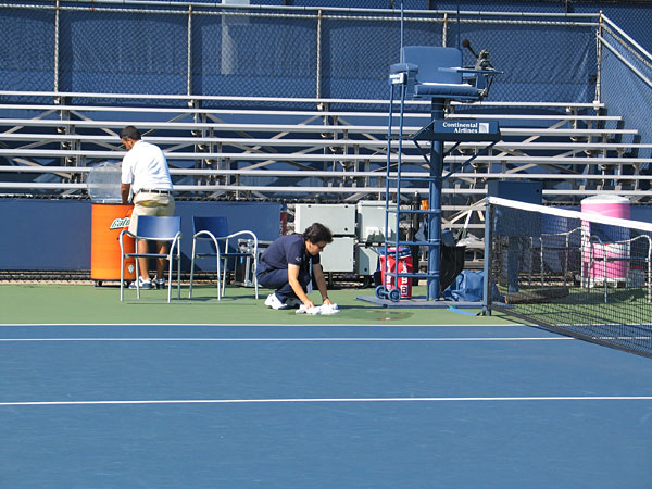 The chair umpire wipes up a puddle on Court 6.