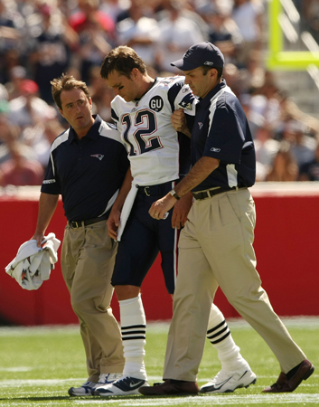 An injured Tom Brady is helped off the field.