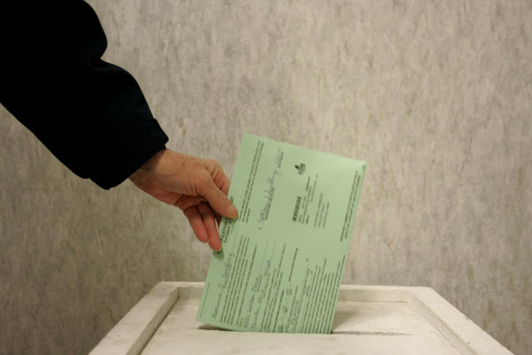 An Ohio woman drops her ballot in a voting box.