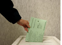 An Ohio woman drops her ballot in a voting box. Click image to expand.