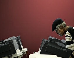 A woman votes using an electronic voting machine. Click image to expand.