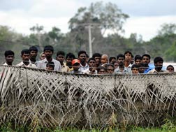 Sri Lankan war-displaced civilians peer from behind barbed wire fences. Click image to expand.