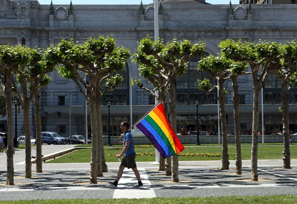 A man carries a gay pride flag through San Francisco's Civic Center Plaza.
