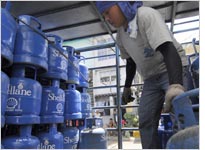A worker moves canisters of liquified petrolum gas (LPG) tanks. Click image to expand.