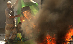 A Libyan rebel burning poster of Qaddafi. Click image to expand.