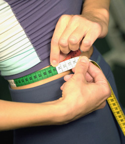 Young woman measuring her waist.