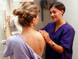 Nurse positioning patient for mammogram.